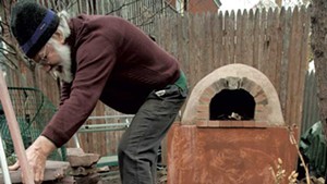 Charlie McClintock finishes the hardscaping around the pizza oven constructed last fall.