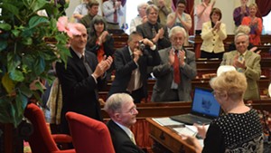 Rep. Joanna Cole (D-Burlington), right,  congratulates House clerk Don Milne (seated) Saturday after Milne's pending retirement was announced. To his left is Bill Magill, who was elected to replace Milne.