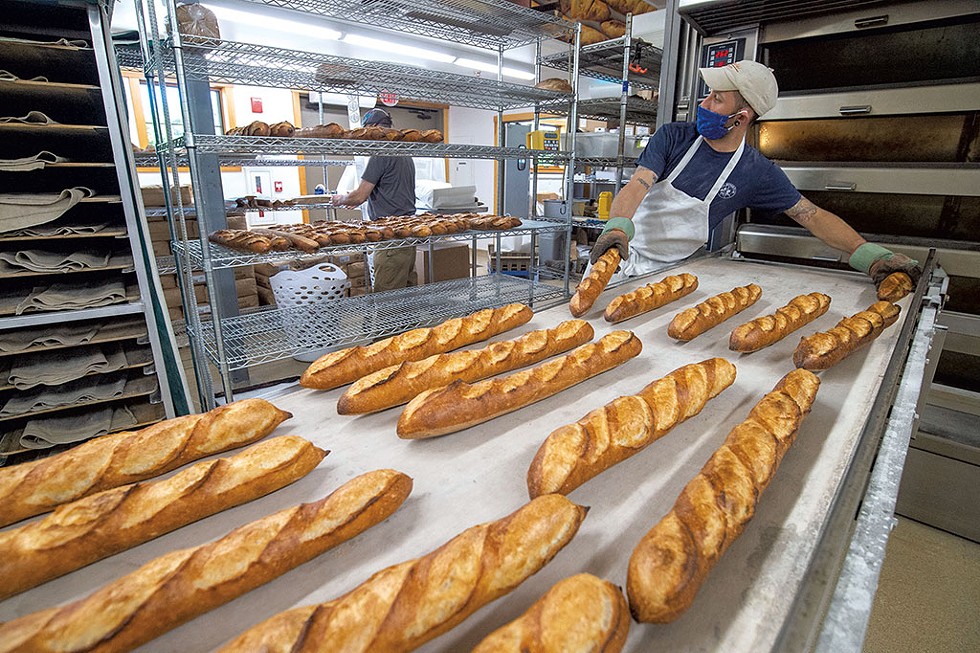 Baker Marc Levy removing fresh-baked baguettes from  the oven - JEB WALLACE-BRODEUR