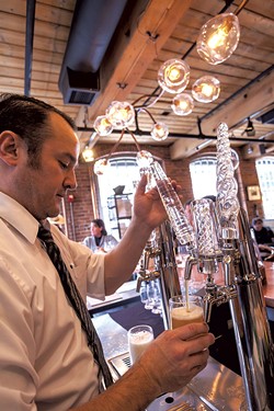 A bartender pulling draft beer with house-blown tap handles - TOM MCNEILL