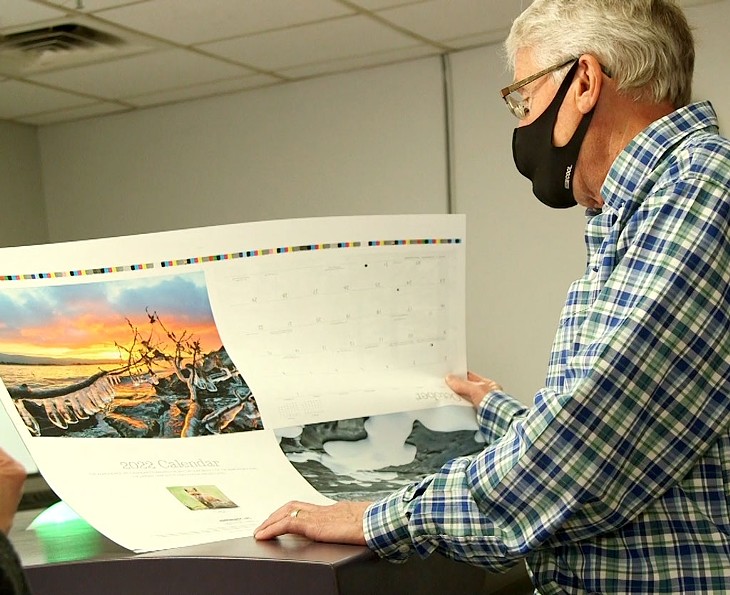 Alan Schillhammer reviewing a printed page for the Adirondack Life calendar - EVA SOLLBERGER ©️ SEVEN DAYS