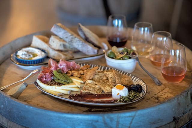 A cheese and charcuterie plate, marinated olives, whipped ricotta with Trent's Bread, and a flight of wine - DARIA BISHOP