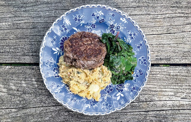 A freshly ground burger with potato salad and wilted greens - SUZANNE PODHAIZER