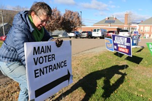 Liz Schlegel Stevens adjusting signs at a polling place in Waterbury Tuesday - KEVIN MCCALLUM
