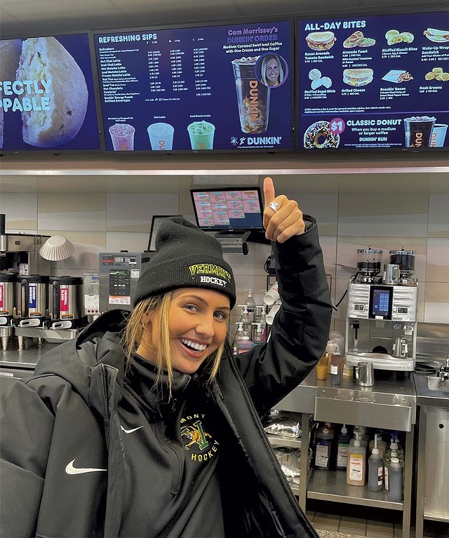Cam Morrissey of the UVM women's ice hockey team in front of the Dunkin' menu - COURTESY