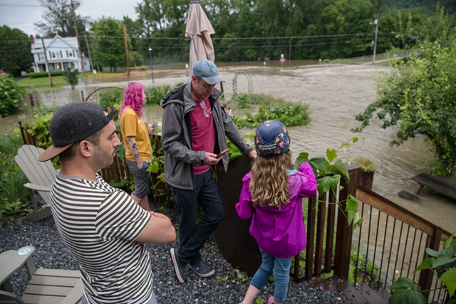 Tyler Stratton (left), co-owner of Stone's Throw Pizza, watching flood waters rise from the terrace of the Richmond restaurant. - DARIA BISHOP
