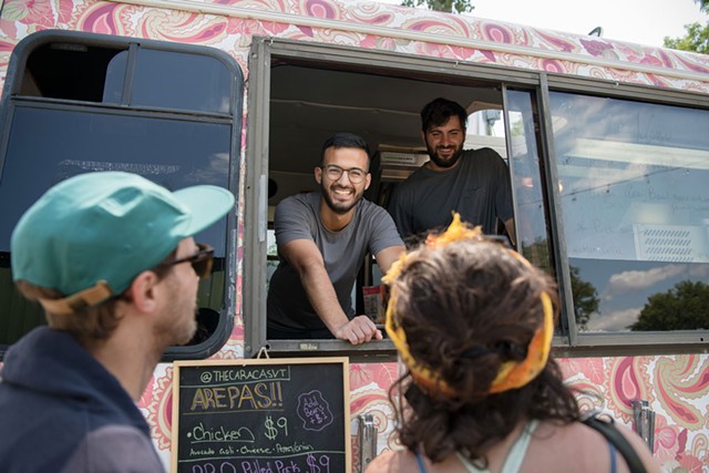 Juan Mejias, upper left, and Facundo Rovira Agosti chatting with customers at the Caracas food truck - DARIA BISHOP