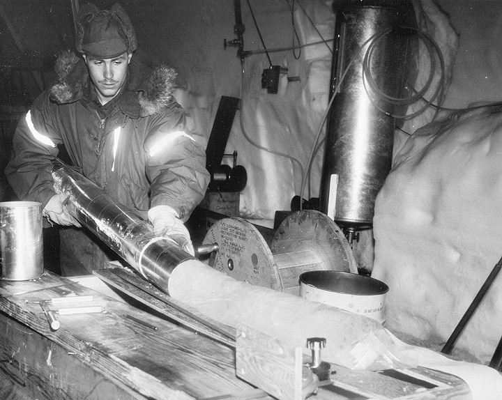 A scientist removing an ice core from its storage tub and placing it on a light table to study layering - COURTESY OF HALLEY MASTRO