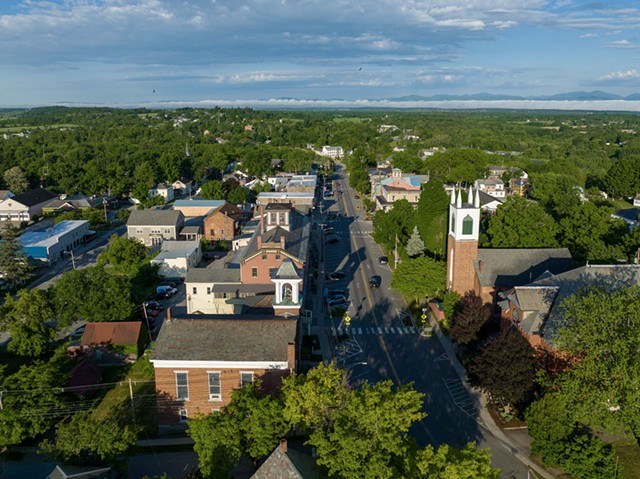 An aerial view of Vergennes showing historic buildings surrounded by trees alongside a street.