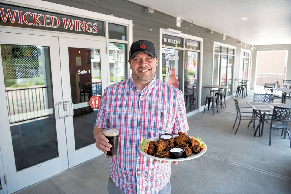 Collin Sourdiff holding a plate of Wicked Wings and a Woodstock Inn &amp; Brewery brown ale - DARIA BISHOP