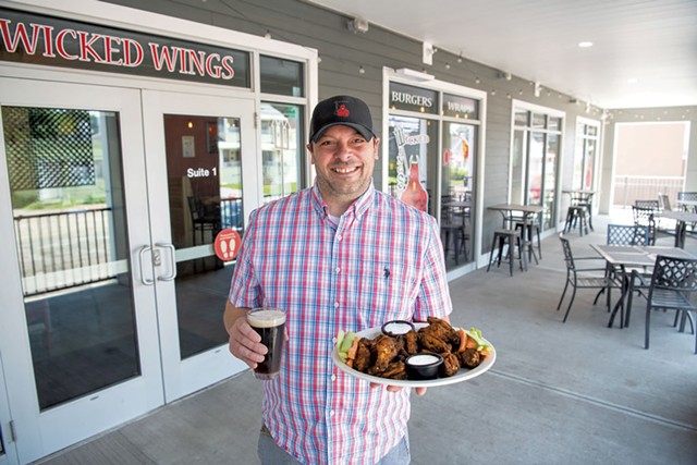 Collin Sourdiff holding a plate of Wicked Wings and a Woodstock Inn & Brewery brown ale - FILE: DARIA BISHOP