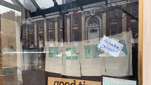 Burlington City Hall is reflected in Good Times Gallery's window.