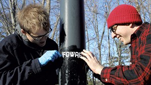 Kason Hudman (left) and Walter Keady trying to remove an Infowars sticker on Riverside Avenue