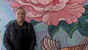 Brian Lewis in front of a mural by Tara Goreau at Filling Station