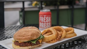 A plant-based burger and onion rings served with a Fresh Press apple cider at Nourish