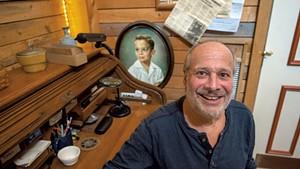 Israel Helfand with a portrait of himself as a child in his Cabot home