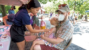 Tristan McNamara holding his daughter Lyra, 4, as she receives a COVID-19 vaccine from nurse Jenna Doran