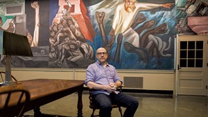 Jeff Sharlet in front of a mural by Mexican artist Jos&eacute; Clemente Orozco titled "The Epic of American Civilization" in Baker-Berry Library at Dartmouth College