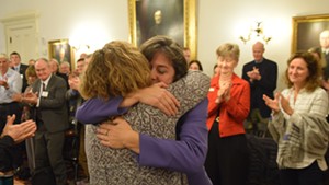 Reps. Mitzi Johnson, in purple, and Sarah Copeland Hanzas hug after Johnson won the vote to be the Democrats’ nominee for House speaker.