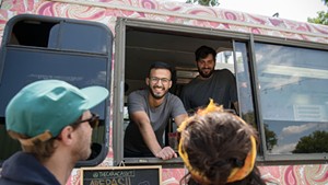 Juan Mejias, upper left, and Facundo Rovira Agosti chatting with customers at the Caracas food truck