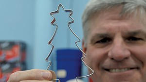Ben Clark holding a Christmas tree cookie cutter at Ann Clark's Rutland manufacturing facility