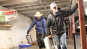 Tino O'Brien and Micheal Sherman help move a dehumidifier out of the basement of Rabble Rouser in Montpelier