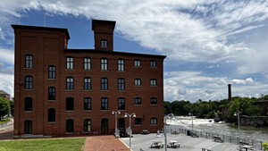 The Champlain Mill, a large brick building with many windows alongside the Winooski River.