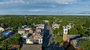 An aerial view of Vergennes showing historic buildings surrounded by trees alongside a street.