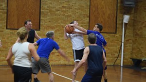Peter Sterling (in blue) blocks a shot by Matt McMahon (in white) during a legislative and staff basketball game Friday.