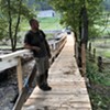 Luke Mulligan on the footbridge he built across the Winooski River